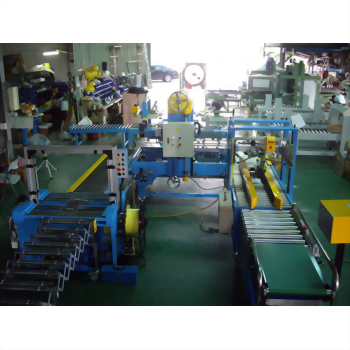 A large blue and yellow industrial packaging machine with multiple conveyor belts and control panels is set up in a factory workshop.