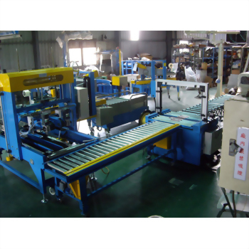 A complex blue and yellow industrial automation system featuring multiple conveyor belts and processing units is shown inside a factory.