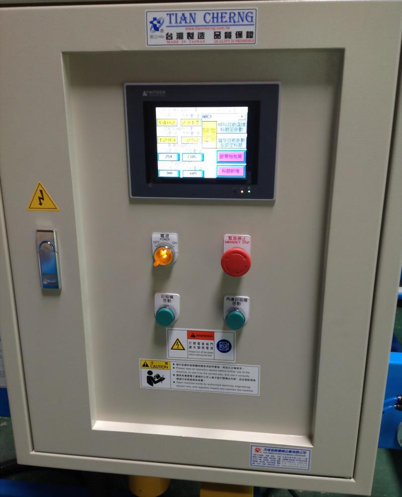 米色機器控制面板，中央黑色螢幕顯示數據，下方有紅、橘、綠色按鈕與開關，並貼有黃色警示標籤。