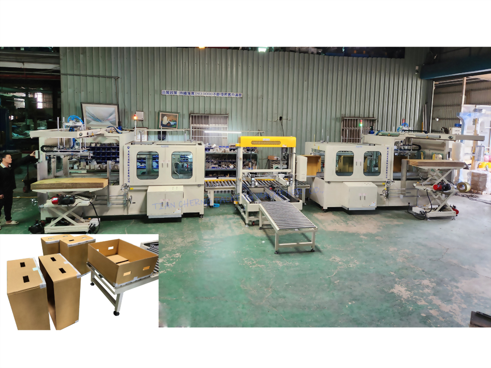 A large, beige automated industrial machine system for forming and packaging cardboard boxes is displayed in a factory, with an inset showing brown boxes.