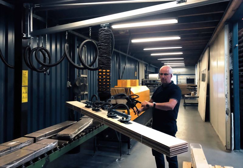 Factory worker vacuum lift wooden panels manufacturing