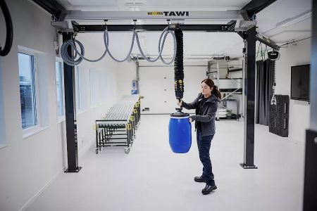 TAWI H 型立柱式懸臂真空吸吊具 - TAWI H 型立柱式懸臂真空吸吊具在倉儲環境中輕鬆搬運一個大型藍色桶子。
