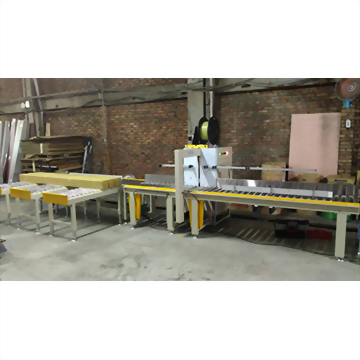 A long industrial production line with yellow and silver components features conveyor belts processing a rectangular yellow insulation block in a factory setting.