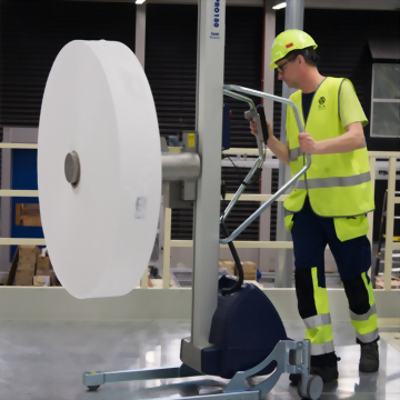 Worker operating industrial lift moving large paper roll
