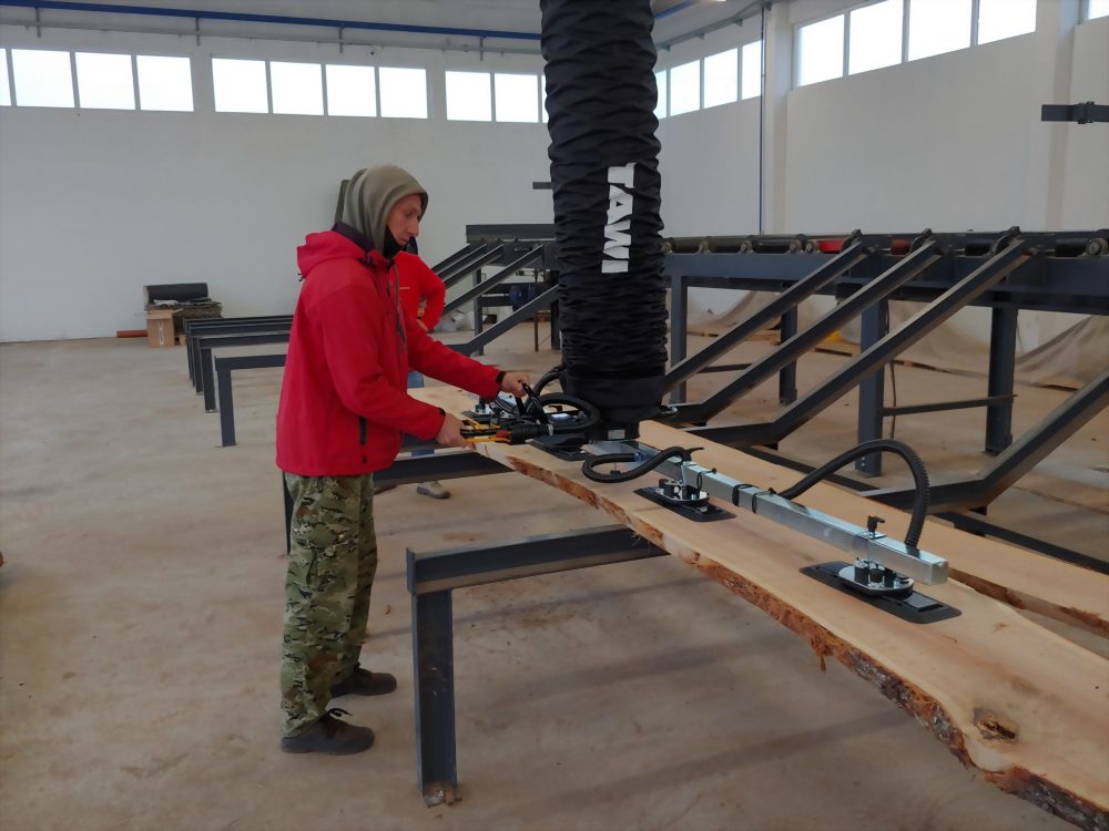 Worker using towi vacuum lifter wood plank workshop