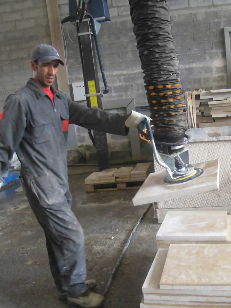 Worker vacuum lifting stone slab workshop